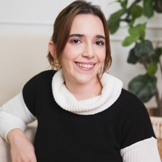 Ana Luiza Castro, psicóloga, sentada em um ambiente claro